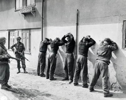 Pfc. Herbert Lusk and Sgt. Joseph F. Mannix guard SS troops captured by units of U.S. 1st Infantry