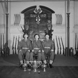Three soldiers are posed in front of the Honourable Artillery Company's war memorial, c1945-c1965