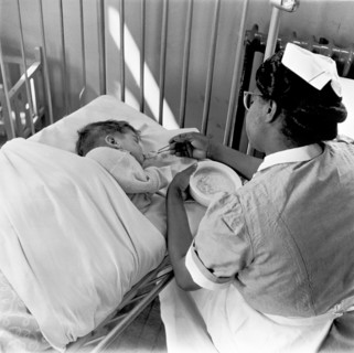 Nurse feeding a child, London, (1960s?). Creator: Henry Grant.