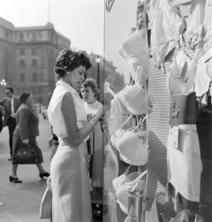 A young woman looking in the window of a lingerie shop in Piccadilly Circus, London, c1946-c1959