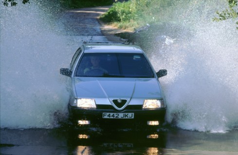 1989 Alfa Romeo 164 driving through a ford. Artist: Unknown.