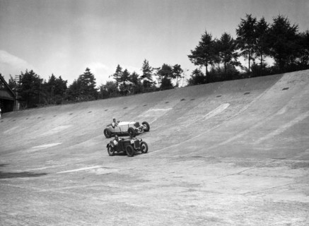 Invicta and Austin Ulster racing on the Members Banking at Brooklands. Artist: Bill Brunell.