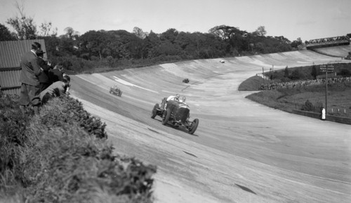 Eddie Hall's Bentley leading a Bugatti on the banking at Brooklands.   Artist: Bill Brunell.