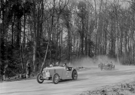 Singer of JR Baker leading a Riley at Coppice Corner, Donington Park, Leicestershire, 1933. Artist: Bill Brunell.