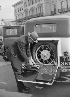 A driver opening the fitted toolkit of his Ford Model A at the Southport Rally, 1928. Artist: Bill Brunell.