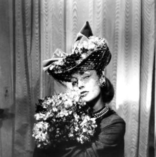 Woman wearing a hat with a veil, holding a bouquet of flowers, Paris, 1943. Artist: Unknown