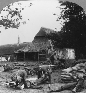 Stretcher bearers caring for wounded at an improvised first aid post, World War I, c1914-c1918.  Artist: Realistic Travels Publishers