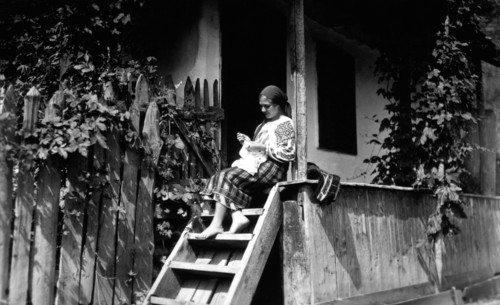 Woman sewing on her porch steps, Bistrita Valley, Moldavia, north-east Romania, c1920-c1945. Artist: Adolph Chevalier