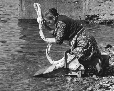 Woman washing clothes in a river, Portugal, 1973.