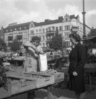 Woman buying potatoes from a fruit and vegetable stall in the market, Malmö, Sweden, 1947. Artist: Otto Ohm