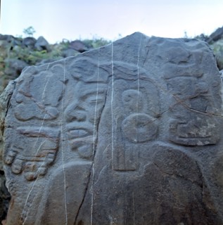 Detail of a sculptural relief on a rock representing a man with a large earring, at his left the ?