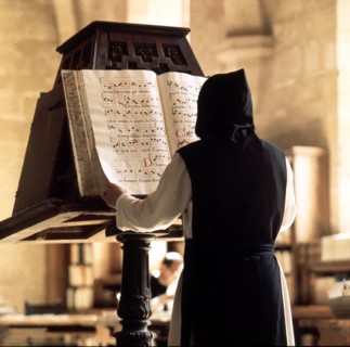 Benedictine monk consulting a song book from the Monastery of Poblet library.