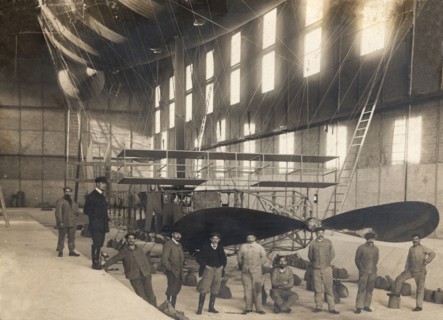 France. Hangar with the cockpit of an airship and a group of mechanics and pilots, 1900s.