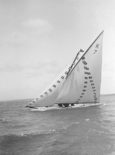 The 7 Metre 'Ginerva' (K7) under sail with prize flags, 1912. Creator: Kirk & Sons of Cowes.