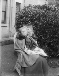 Woman sitting in a chair in a garden, c1900. Creator: Kirk & Sons of Cowes.