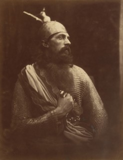 The Passing of King Arthur, 1874. A melodramatic depiction of Arthur?s death scene.  A bearded man (William Warder) in profile, wearing chainmail and an armour helmet with his right hand gripping a sw...