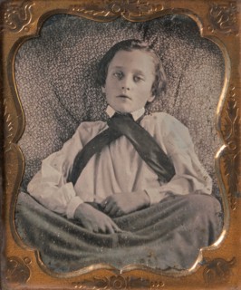 Boy Seated Cross-legged, Partially Covered by Blanket, Leaning Against Cushion, 1850s.