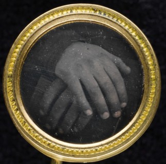 Two hands resting on a book set into a two-piece gold-washed brass frame