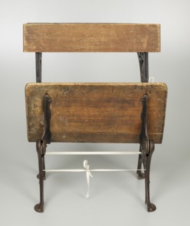 Wood and iron school desk with a foldable seat.