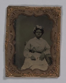 Tintype of a woman wearing a striped dress with flowers in her hair, 1855-1860s. Creator: Unknown.