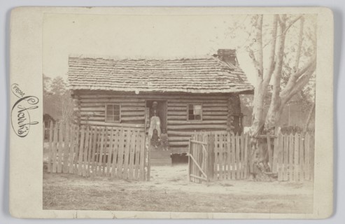 Albumen print of a woman and two children in front of a log house in Georgia, 1880s. Creator: H. S. Clark.