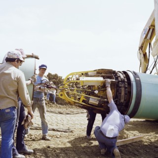 A team of men joining two steel pipes together on the Martin pipeline, Hertfordshire, 07/07/1981. Creator: John Laing plc.