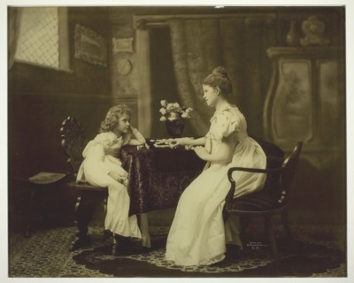 Woman and Child Playing Dominoes at Table, c. 1898. Creator: Unknown.