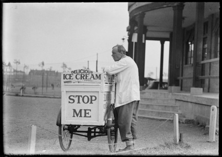 An Eldorado ice cream seller standing beside his tricycle cart outside a pavilion, 1930s. Creator: Charles William  Prickett.