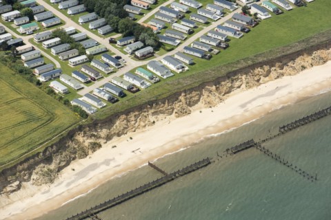 Coastal erosion between a caravan park and the sea defences at Corton Cliffs, Suffolk, 2019. Creator: Historic England.