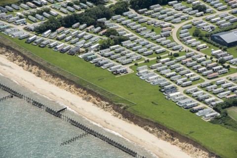 Coastal erosion between a caravan park and the sea defences at Corton Cliffs, Suffolk, 2019. Creator: Historic England.