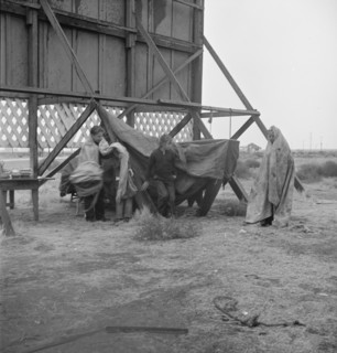 One of three families camped behind a billboard on U.S. 99, Kern County, California, 1938. Creator: Dorothea Lange.
