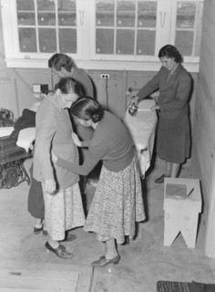Camper receives help in fitting a coat from WPA sewing instructor, FSA, California, 1938. Creator: Dorothea Lange.