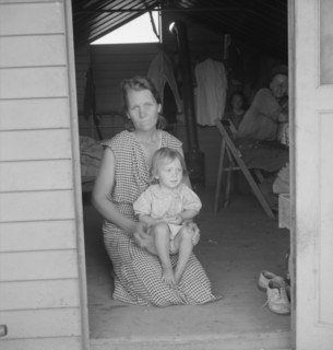 Migrant mother and child at doorway of steel shelter, FSA camp, Tulare County, 1939. Creator: Dorothea Lange.