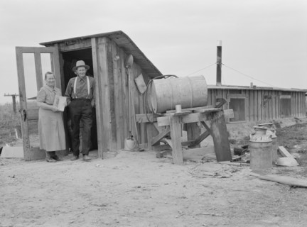 Mr. and Mrs. Wardlow at entrance to their dugout basement home, Dead Ox Flat, Oregon, 1939 Creator: Dorothea Lange.