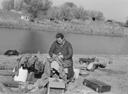 Mother of migrant family sewing. Near Vale, Malheur County, Oregon.