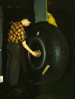 Inspecting of landing wheel of the transport planes at Willow Run, between 1941 and 1945. Creator: Howard Hollem.