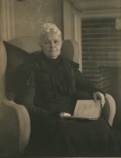 Old woman in an armchair, with an open book in her lap, c1900.