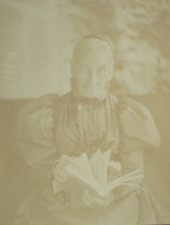 Elderly woman sitting in a chair holding a book, half-length portrait, facing front, c1890.