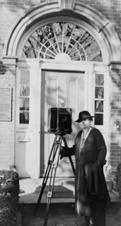Frances Benjamin Johnston, full-length portrait, standing in front of door, with camera..., c1935. Creator: Unknown.
