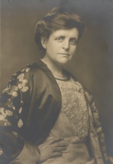 Frances Benjamin Johnston, half-length portrait, turned to the right, facing front, with right hand on hip, 1911.
