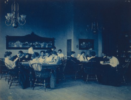 Students seated around tables, studying, at Western High School, Washington, D.C., (1899?).