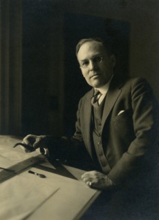 Leicester B. Holland, Chief of Fine Arts Division, Library of Congress posed...table, (1930?). Creator: Frances Benjamin Johnston.