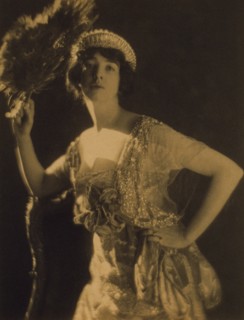 Three-quarter length portrait of Gertrude Vanderbilt Whitney...holding a peacock feather fan, c1916. Creator: Adolph de Meyer.