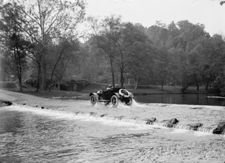 Couple In Automobile Fording A River At A Low Water Crossing Near A Small Stone Bridge, between 1913 and 1918.
