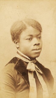 Portrait of young woman with velvet lapels and ribbon bow around neck, (1880-1889?). Creator: LV Bean.