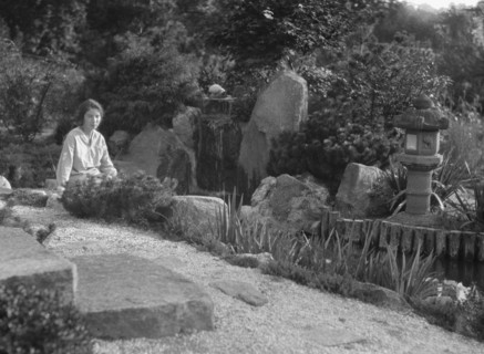 Unidentified woman seated in a garden next to a stream, possibly belonging to A.W. Bahr, c 1917-1934 Creator: Arnold Genthe.