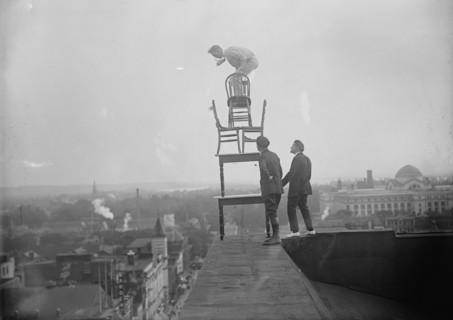 J. Reynolds, Performing Acrobatic And Balancing Acts On High Cornice Above 9th Street, N.W., 1917. Creator: Harris & Ewing.