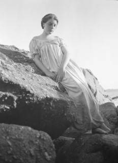 Wilson, Helen, Mrs., seated on rocks at the beach, between 1906 and 1928. Creator: Arnold Genthe.