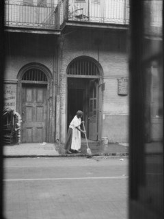 View from across street of a woman cleaning the sidewalk, New Orleans, between 1920 and 1926. Creator: Arnold Genthe.