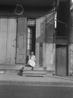 View from across street of a woman sitting on steps, New Orleans, between 1920 and 1926. Creator: Arnold Genthe.